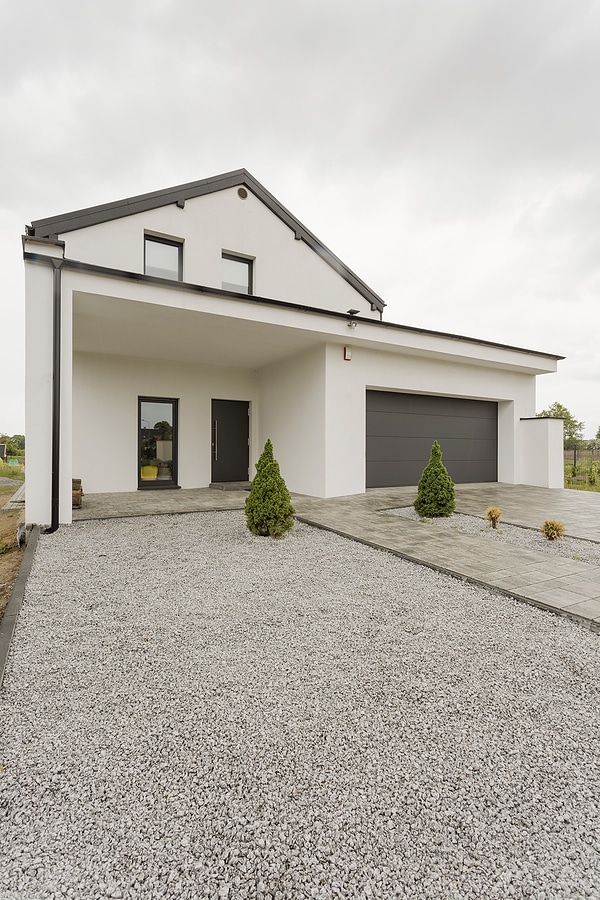 Front view of modern white house exterior and gravel driveway.